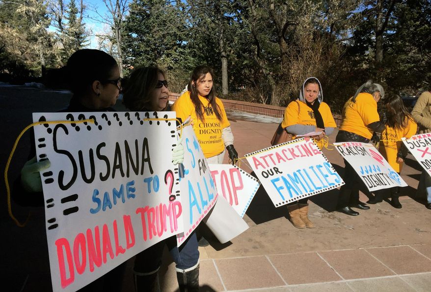 In this Tuesday, Jan. 19, 2016 photo demonstrators from the Santa Fe-based immigrant advocate group Somos Un Pueblo Unido hold signs outside the capitol in Santa Fe, N.M. to protest New Mexico Gov. Susana Martinez's attempt to revise the state's immigrant driver's license law. (AP Photo/Russell Contreras)