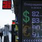 People walk past an exchange office screen showing the currency exchange rates of the Russian ruble, U.S. dollar and euro in Moscow, Russia, Thursday, Jan. 21, 2016. The Russian ruble has hit another historic low against the dollar as oil prices continue to slide due to a surplus of crude oil on world markets. (AP Photo/Alexander Zemlianichenko)