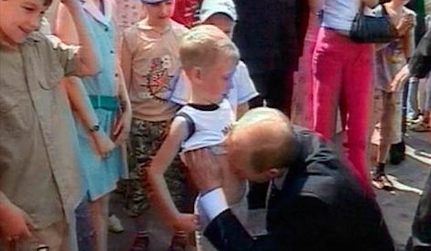 Russian President Vladimir Putin lifts the shirt of a young boy named Nikita and kisses his stomach June 28 at the Kremlin in Moscow, in this image taken from Russian state television. (Associated Press, file)