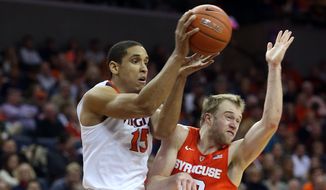 Virginia guard Malcolm Brogdon (15) passes the ball next to Syracuse guard Trevor Cooney (10) during an Atlantic Coast Conference basketball game, Sunday Jan. 24, 2016, in Charlottesville, Va. Virginia  defeated Syracuse 73-65. (AP Photo/Andrew Shurtleff)