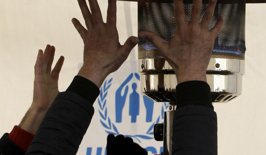 Refugees try to warm themselves up in a tent at the transit center for refugees near northern Macedonian village of Tabanovce, before continuing their journey to Serbia, on Sunday, Jan. 24, 2016. Macedonia, Serbia and Croatia, the countries on the so-called Balkan migrant corridor that starts in Greece, are only letting in people whose stated final destination is Germany or Austria. (AP Photo/Boris Grdanoski)
