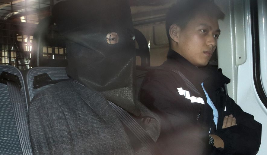 Chinese fugitive Deyun Shi, left, escorted by a police officer in a police van, arrives at a magistrate court in Hong Kong Monday, Jan. 25, 2016. Shi who was arrested early Sunday in Hong Kong after arriving on a flight from Los Angeles in connection with the slayings of his teenage nephews in California has told the court he won't fight extradition to the United States. (AP Photo/Vincent Yu)