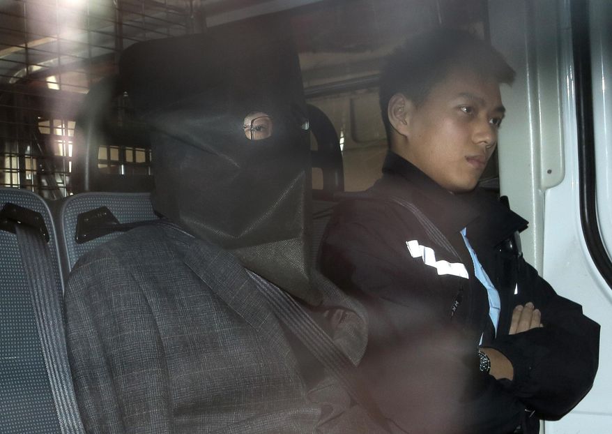 Chinese fugitive Deyun Shi, left, escorted by a police officer in a police van, arrives at a magistrate court in Hong Kong Monday, Jan. 25, 2016. Shi who was arrested early Sunday in Hong Kong after arriving on a flight from Los Angeles in connection with the slayings of his teenage nephews in California has told the court he won't fight extradition to the United States. (AP Photo/Vincent Yu)