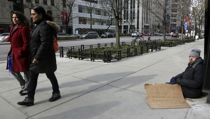A man, right, panhandles on the street Monday, Jan. 25, 2016, in Chicago. A lawsuit brought by panhandlers who say they lose up to $10 a day because authorities bar them from a popular public square in Chicago is set to go to trial. The trial that starts Monday in Chicago federal court is a rare instance of jurors being asked to decide the issue of panhandlers' rights. (AP Photo/M. Spencer Green)