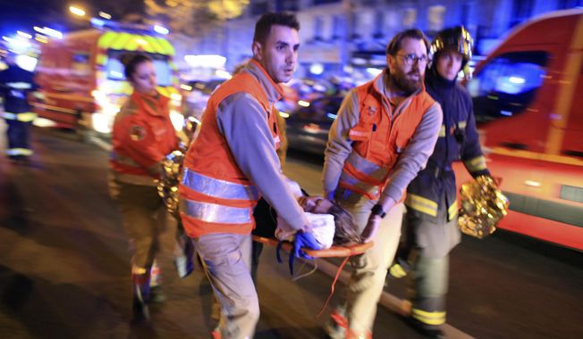 In this Nov. 13, 2015, file photo, a woman is evacuated from the Bataclan concert hall after gunmen attacked the venue in Paris. (AP Photo/Thibault Camus, File)