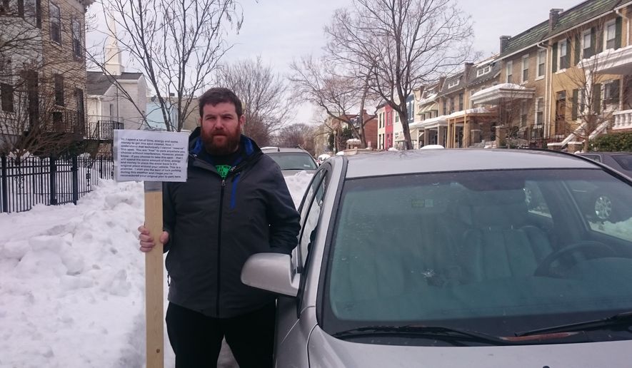 Nathan Bergman holds a sign he authored to keep people out of a parking space after this weekend&#39;s blizzard. (Andrea Noble/The Washington Times)