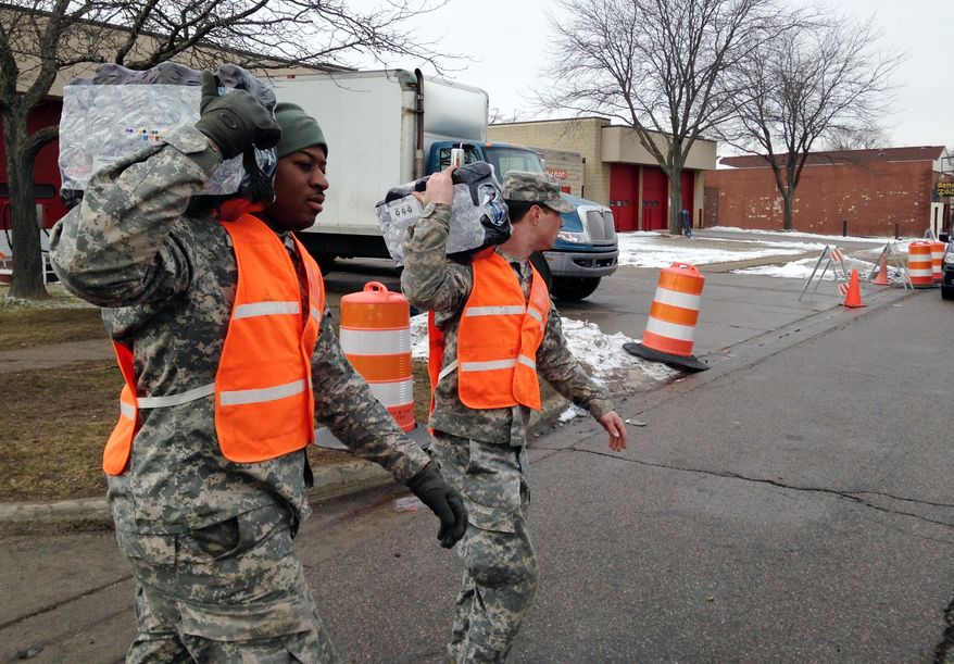 In this photo taken Friday, Jan. 22, 2016, National Guardsmen carry water to a resident’s car in Flint, Mich. Residents across the city have been forced to rely on bottled water after leached pipes brought lead and other dangerous substances into homes. (AP Photo/Matt Sedensky)