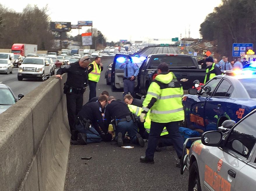 First responders are shown working on a suspect that was shot following a chase on Interstate 75 in Cobb County. A state trooper and a suspect were shot Wednesday, Jan. 27, 2016, in a police chase in suburban Atlanta, the Georgia State Patrol said. The GSP said in an email that the trooper and suspect were shot in a pursuit on Interstate 75 in Marietta. (Johnny Edwards/Atlanta Journal-Constitution via AP)