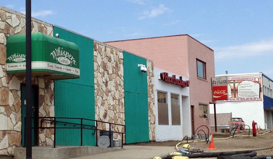 FILE - This Aug. 11, 2014 file photo shows two strip clubs along Main Street in Williston, N.D. The Williston City Commission is banning strip clubs downtown and an attorney for one of the two existing clubs says he's considering a lawsuit. The commission on Tuesday, Jan. 26, 2016, gave final approval to ordinances restricting all exotic dancing to industrial zones on the city's outer fringe within a year. (AP Photo/Josh Wood, File)