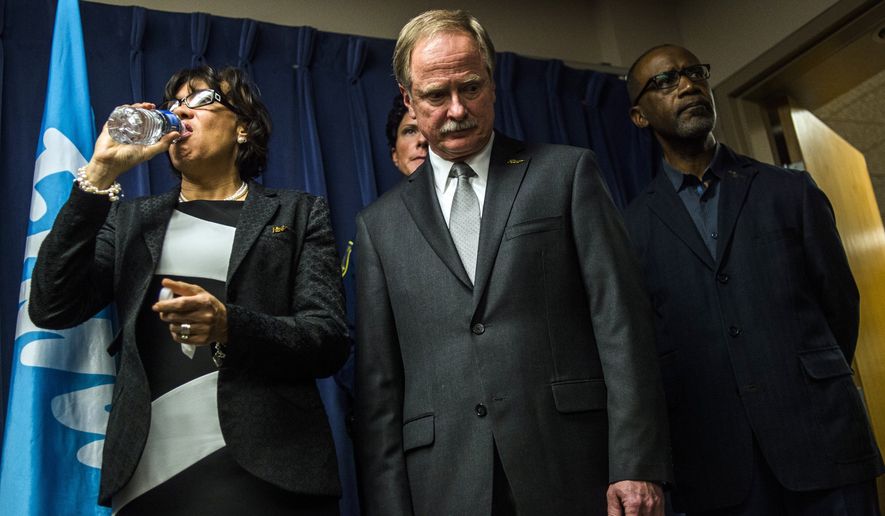 Flint Mayor Karen Weaver drinks from a bottle of water beside Michigan Department of Environmental Quality Director Keith Creagh as Gov. Rick Snyder fields questions from reporters about the Flint water crisis. (Jake May /The Flint Journal-MLive.com via AP) LOCAL TELEVISION OUT; LOCAL INTERNET OUT; MANDATORY CREDIT