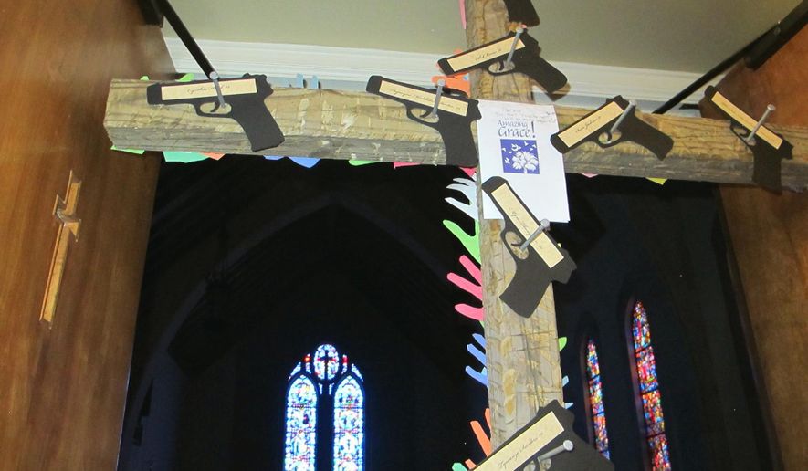A cross with cutouts of handguns and the names of the nine victims of the Charleston church shootings stands at the door to the chapel at Washington Street United Methodist Church in Columbia, S.C., on Friday, Jan. 29, 2016. Parishioners attending a Stand-Up Sunday service at the chapel on Jan. 31 will pass under the cross. An estimated 1,300 congregations of all denominations in South Carolina are participating in the Stand-Up Sunday to draw attention to the national epidemic of gun violence and seek tighter gun laws while respecting people's rights to own guns. (AP Photo/Bruce Smith)