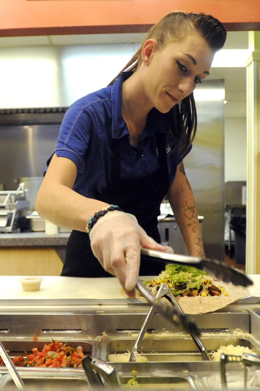 FOR RELEASE SATURDAY, JANUARY 30, 2016, AT 12:01 A.M. MST. - Christine Reyes carefully grabs some lettuce for a burrito on Wednesday at the Qdoba off of 11th Avenue in Greeley, Colo. Qdoba is experimenting by paying employees $11 an hour for 3 months to create more stability in their work force. (Joshua Polson/The Greeley Tribune via AP)