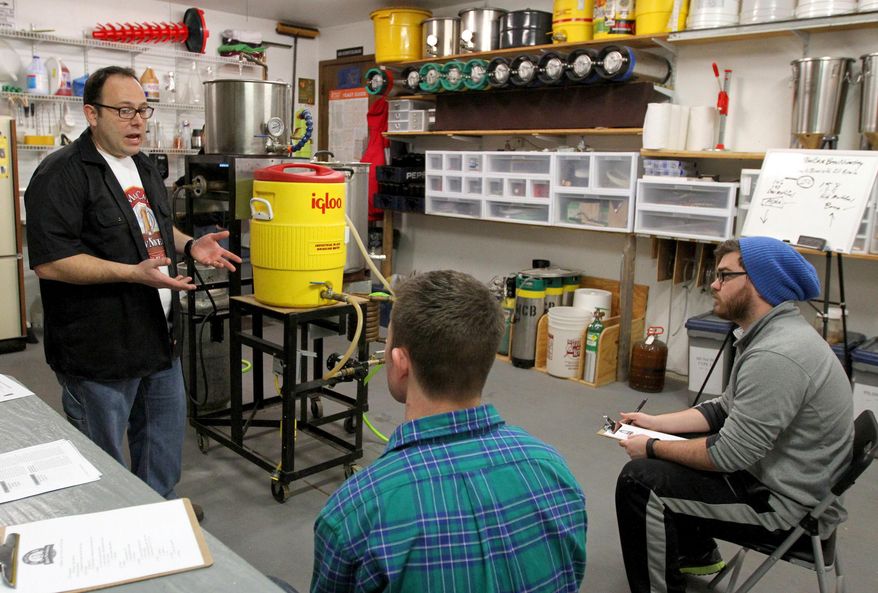 In this photo taken on Saturday, Jan. 16, 2016, Jason Gabriel, left, of Davenport teaches a home brewing class to John McAfoos, foreground left, of Davenport and Christian LaCarte of Parkview, in his garage in Davenport, Iowa. Gabriel calls his business Man Cave BrewNiversity. (John Schultz /Quad City Times via AP) MANDATORY CREDIT