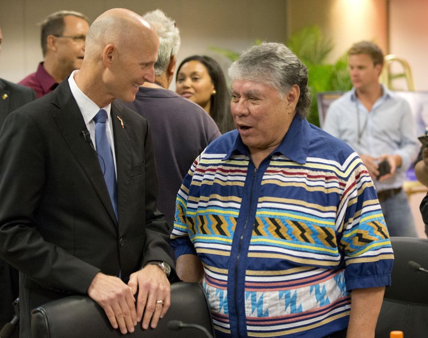 Gov. Rick Scott, left, talks with James Billie, Seminole Tribe of Florida chairman, at the tribe's headquarters, Monday, Feb. 1, 2016, in Hollywood, Fla. The tribe is seeking to increase pressure on state lawmakers to approve a new gaming compact by unveiling a $1.8 billion expansion plan at the tribe's Hollywood and Tampa locations that would potentially create thousands of jobs. Scott and Billie signed the new compact in December, but so far it has languished in the legislature. (AP Photo/Wilfredo Lee)
