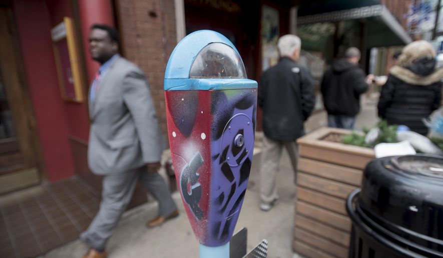 A man walks by a parking meter with work designed by graffiti artist Antonio "Shades" Agee on Tuesday, Feb. 2, 2016 in Detroit. A new initiative in downtown Detroit uses repurposed parking meters to collect donations for nonprofits that serve the homeless. The first phase of the “Detroit Donates” campaign launched Tuesday with 17 meters in both public and private spaces. The initial pilot phase will be concentrated in the city’s central business district, with plans to expand next into Campus Martius Park. (David Guralnick/Detroit News via AP) DETROIT FREE PRESS OUT; HUFFINGTON POST OUT; MANDATORY CREDIT
