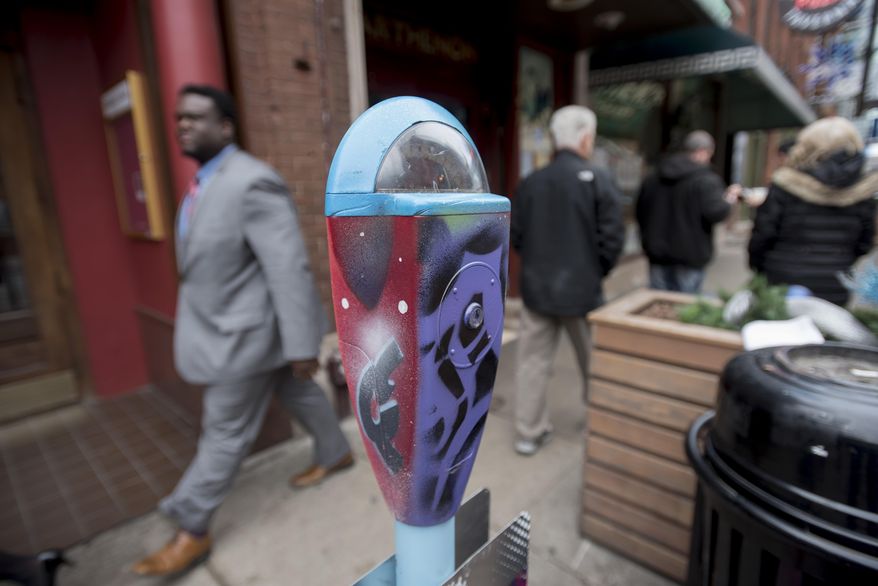 A man walks by a parking meter with work designed by graffiti artist Antonio "Shades" Agee on Tuesday, Feb. 2, 2016 in Detroit. A new initiative in downtown Detroit uses repurposed parking meters to collect donations for nonprofits that serve the homeless. The first phase of the “Detroit Donates” campaign launched Tuesday with 17 meters in both public and private spaces. The initial pilot phase will be concentrated in the city’s central business district, with plans to expand next into Campus Martius Park. (David Guralnick/Detroit News via AP) DETROIT FREE PRESS OUT; HUFFINGTON POST OUT; MANDATORY CREDIT