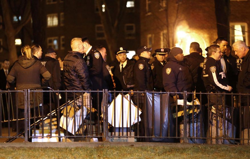 Emergency officials gather near the site where two police officers were shot in the Bronx section of New York, Thursday, Feb. 4, 2016. Two police officers were shot while on patrol in a public housing project on Thursday night and suffered non-life-threatening injuries, and a suspect was in custody, authorities said. (AP Photo/Julio Cortez)