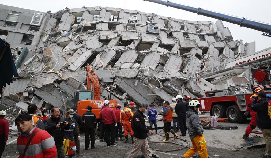 Rescue workers search a collapsed building from an early morning earthquake in Tainan, Taiwan, Saturday, Feb. 6, 2016. A powerful, shallow earthquake struck southern Taiwan before dawn Saturday. (AP Photo/Wally Santana)