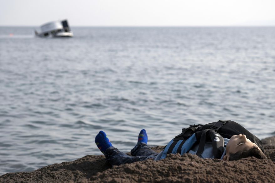 The dead body of a migrant boy lies on the beach near the Aegean town of Ayvacik, Canakkale, Turkey, Saturday, Jan. 30, 2016. A boat carrying migrants to Greece hit rocks off the Turkish coast on Saturday and capsized, killing dozens, including children, according to officials. (AP Photo/Halit Onur Sandal)