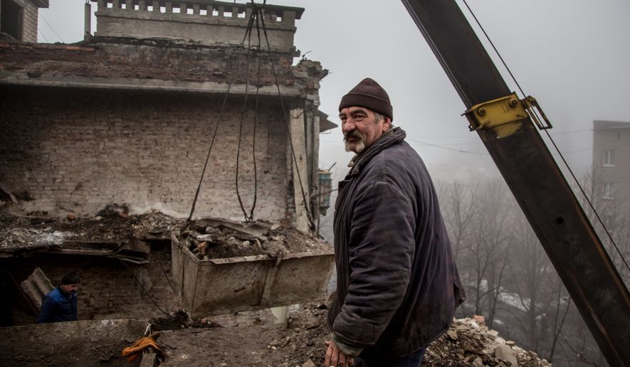 In this photo taken on Wednesday, Feb. 3, 2016, a construction worker removes rubble from the roof of a severely damaged condo in Debaltseve, eastern Ukraine. Money from Russia helps to the rebuild eastern Ukrainian town of Debaltseve, a strategic rail hub that rebels pounded for weeks before driving out the government troops a year ago. But there has been little or no money to spare for the nearby villages, which still bear the scars of one of the fiercest battles of the war. (AP Photo/Petr Anikukhin)