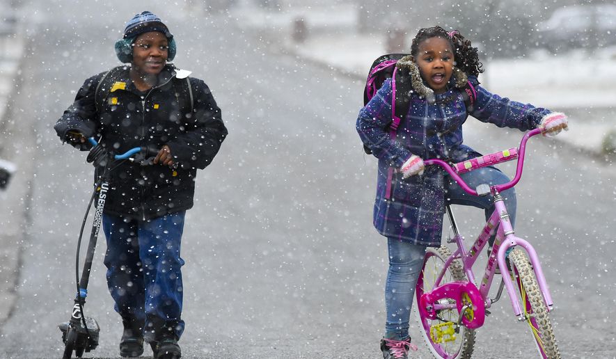 West Decatur Elementary students, Kelvin and Flowah Harris arrive at school in Decatur, Ala., through a shower of snowflakes, Tuesday, Feb. 9, 2016. (John Godbey/The Decatur Daily via AP) MANDATORY CREDIT