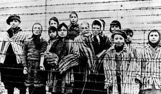 This file photo taken just after the liberation by the Soviet army in January 1945 shows a group of children wearing concentration camp uniforms behind barbed wire fencing in the Oswiecim (Auschwitz) Nazi concentration camp. A 94-year-old former SS guard at the Auschwitz death camp is going on trial Thursday, Feb. 11, 2016, on 170,000 counts of accessory to murder, the first of up to four cases being brought to court this year in an 11th-hour push by German prosecutors to punish Nazi war crimes. (AP Photo)