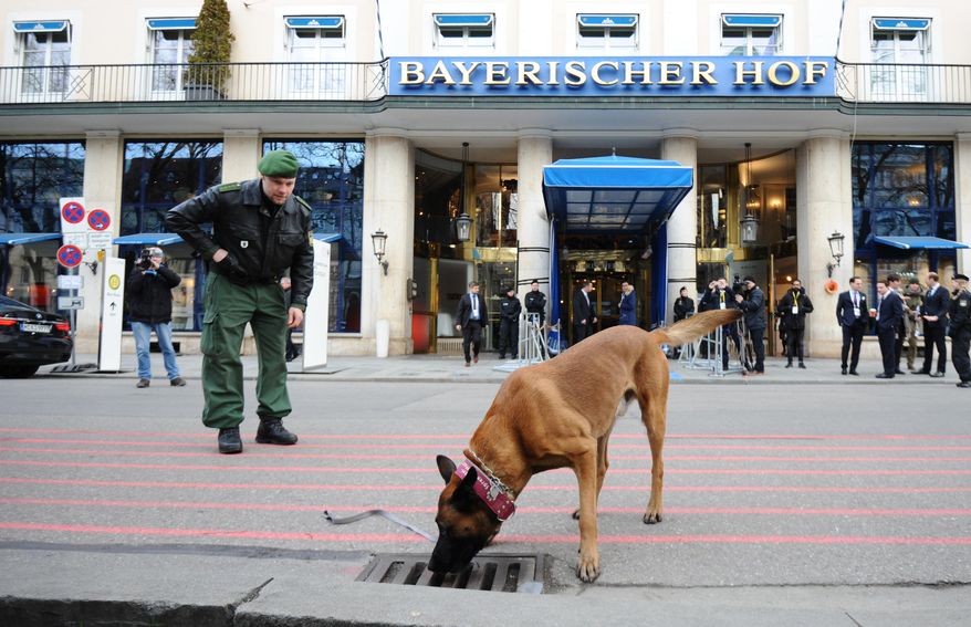A German policeman inspects the area around the international security conference with a sniffer dog in Munich, southern Germany, Friday, Feb. 12, 2016. The Munich Security Conference, an annual gathering of foreign and defense policy leaders, opens Friday and lasts until Sunday. (Andreas Gebert/dpa via AP)