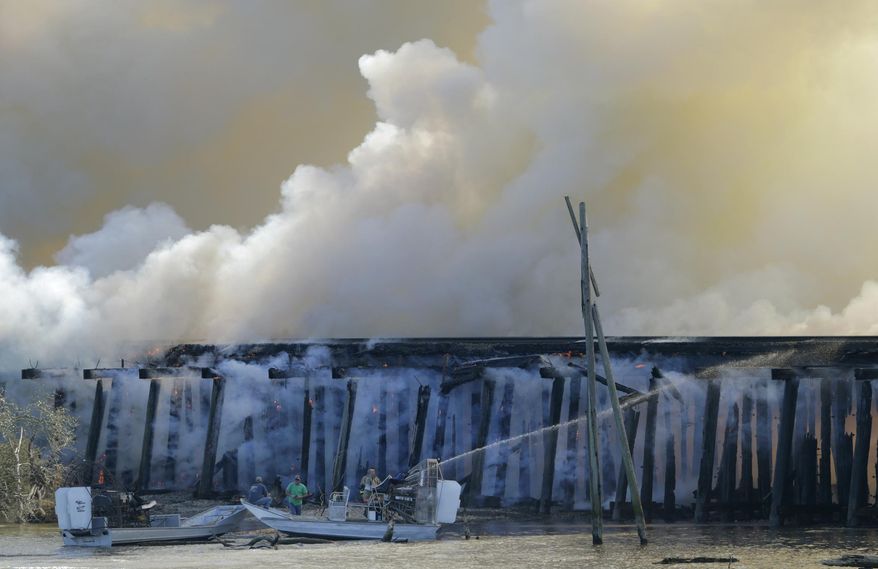 A fire burns on a train trestle parallel to Interstate 10 near the Bonnet Carre Spillway, west of New Orleans on Saturday, Feb. 13, 2016. A CN Railway spokesman says it typically carries four to eight freight trains a day, plus one passenger train in each direction. (Brett Duke/NOLA.com The Times-Picayune via AP)