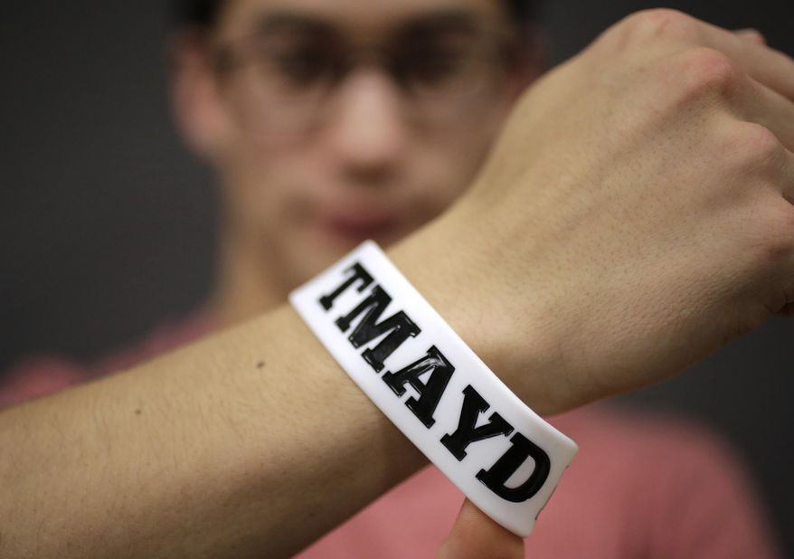 In this Monday, Feb. 1, 2016 photo, Massachusetts Institute of Technology student Andy Trattner, of Portland, Ore., displays a wrist band that features the acronym TMAYD for &amp;quot;Tell Me About Your Day,&amp;quot; a campaign to encourage students to talk to one another in an effort to defuse to the stress of campus life before it leads to a crisis. There were several campus suicides last year. MIT officials recently set aside thousands of dollars for grants to help support campus projects dealing with mental health. (AP Photo/Steven Senne)