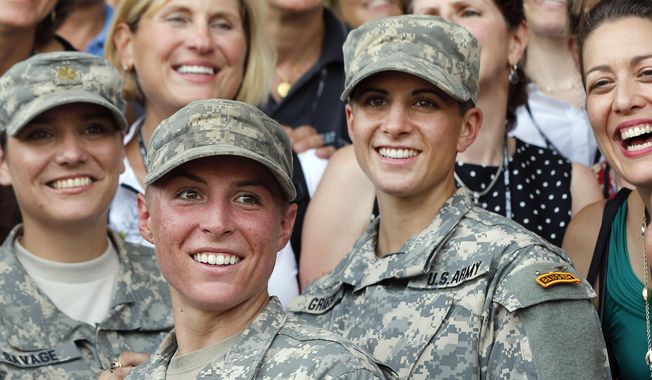 In this Aug. 21, 2015, file photo, Army 1st Lt. Shaye Haver, center, and Capt. Kristen Griest, right, pose for photos with other female West Point alumni after an Army Ranger school graduation ceremony at Fort Benning, Ga. In a Feb. 25, 2021 essay for West Point&#x27;s Modern War Institute, Capt. Griest said the Army shouldn&#x27;t go back to the old system where men and women were graded differently on PT tests.  (AP Photo/John Bazemore, File)   **FILE**
