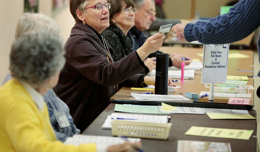 Chief inspector Jeanne Thieme inspects a voter's identification card at the Olbrich Gardens polling location in Madison, Wis. Tuesday, Feb. 16, 2016. The Supreme Court election was the only statewide race in Tuesday’s primary, which included scattered county and municipal races. Turnout was projected at only around 10 percent. A photo ID was required to vote, a new requirement stemming from a law first passed in 2011 but eventually put on hold until it was upheld by the state Supreme Court in one of several rulings seen as partisan in recent years. (Michael P. King/Wisconsin State Journal via AP) MANDATORY CREDIT