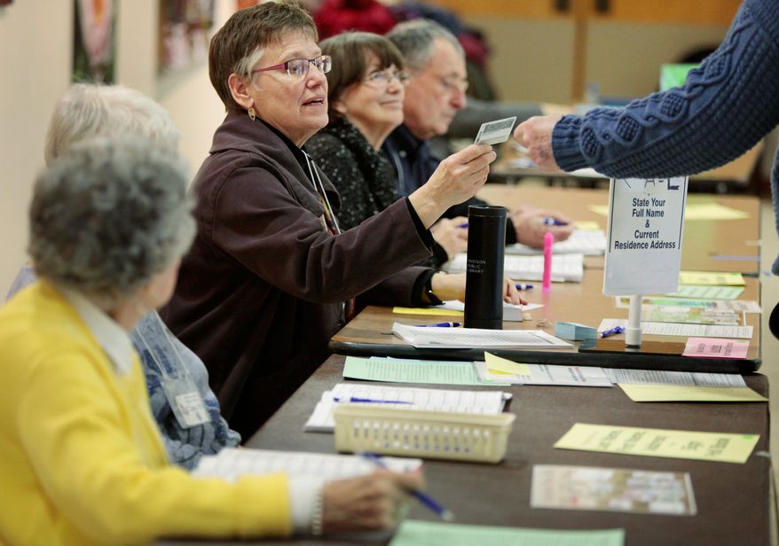 Chief inspector Jeanne Thieme inspects a voter's identification card at the Olbrich Gardens polling location in Madison, Wis. Tuesday, Feb. 16, 2016. The Supreme Court election was the only statewide race in Tuesday’s primary, which included scattered county and municipal races. Turnout was projected at only around 10 percent. A photo ID was required to vote, a new requirement stemming from a law first passed in 2011 but eventually put on hold until it was upheld by the state Supreme Court in one of several rulings seen as partisan in recent years. (Michael P. King/Wisconsin State Journal via AP) MANDATORY CREDIT
