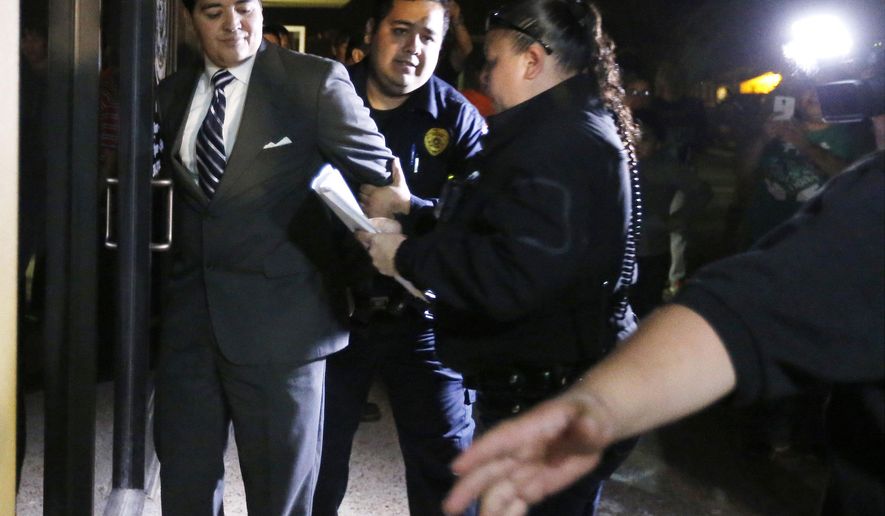In this photo taken on Tuesday, Feb. 16, 2016, Crystal City Mayor Ricardo Lopez is taken away from city hall by police, in Crystal City, Texas, after allegedly disrupting a City Council meeting while fighting a recall effort that began before his indictment this month in a public corruption investigation that has ensnarled him and most of the council. (Kin Man Hui /The San Antonio Express-News via AP) RUMBO DE SAN ANTONIO OUT; NO SALES; MANDATORY CREDIT