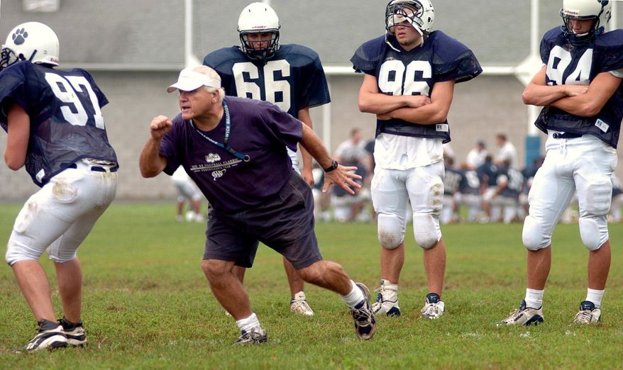 FILE - In this Aug. 16, 2004, file photo, Berwick High School football coach George Curry, second from left, demonstrates techniques during blocking and tackling drills at Crispin Field in Berwick, Pa. Curry, whose 455 victories over a 46-year career are the most by a Pennsylvania high school football coach, was diagnosed midway through the 2015 football season with Lou Gehrig's disease, also called amyotrophic lateral sclerosis or ALS. The players, from left, are Seth Fetterolf, Nick Corridini, Jake Fetterolf and Keith Ball. (Bill Hughes/Bloomsburg Press Enterprise via AP, File) MANDATORY CREDIT