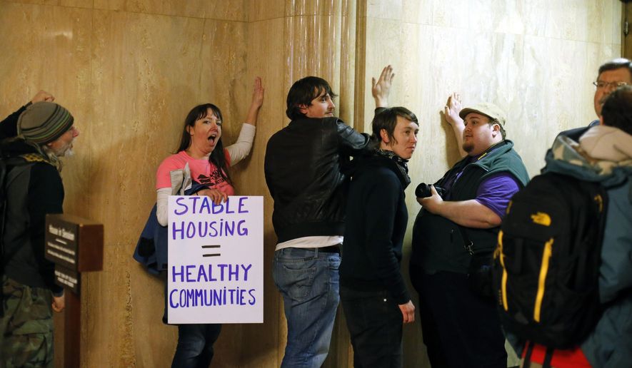 Protesters pound on the walls outside of the House Chamber in the Capitol Building, in Salem , Ore., on Thursday, Feb. 18, 2016. The group were protesting for a higher minimum wage, local control of rent control laws, and an end to Oregon Department of Transportation sweeps of homeless camps. (AP Photo/Timothy J. Gonzalez)