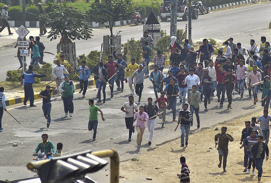 Protesters run some with sticks during a pro caste quota protest in Rohtak, 70 kilometers (45 miles) west of New Delhi, India, Friday, Feb. 19, 2016. India's paramilitary forces shot and killed one person on Friday as protests for government benefits turned violent in northern India, police said. Thousands of people belonging to the Jat agricultural community were protesting in Rohtak and other towns in Haryana state, to demand an increase in their caste quota benefits, which include guaranteed government jobs or university spots. (AP Photo/Deepak Khanna) NO ARCHIVES NO SALES