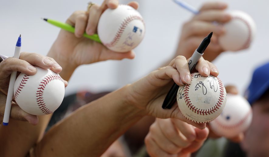 Fans hold out baseballs in hopes of getting an autograph following the New York Mets' spring training baseball practice Saturday, Feb. 20, 2016, in Port St. Lucie, Fla. (AP Photo/Jeff Roberson)