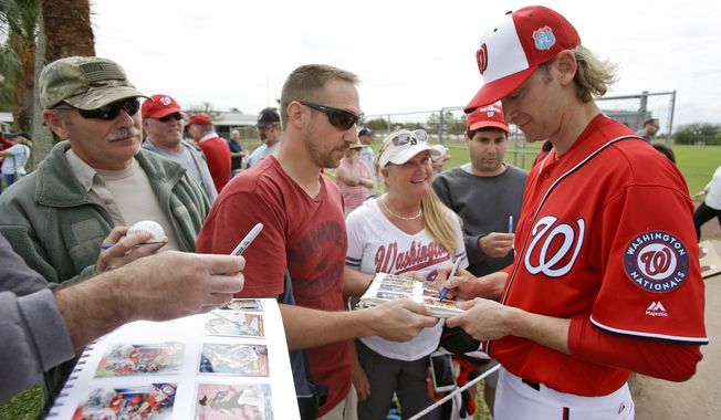 Bronson Arroyo, right, signs autographs for fans during a spring training baseball workout, Saturday, Feb. 20, 2016, in Viera, Fla. (AP Photo/John Raoux)