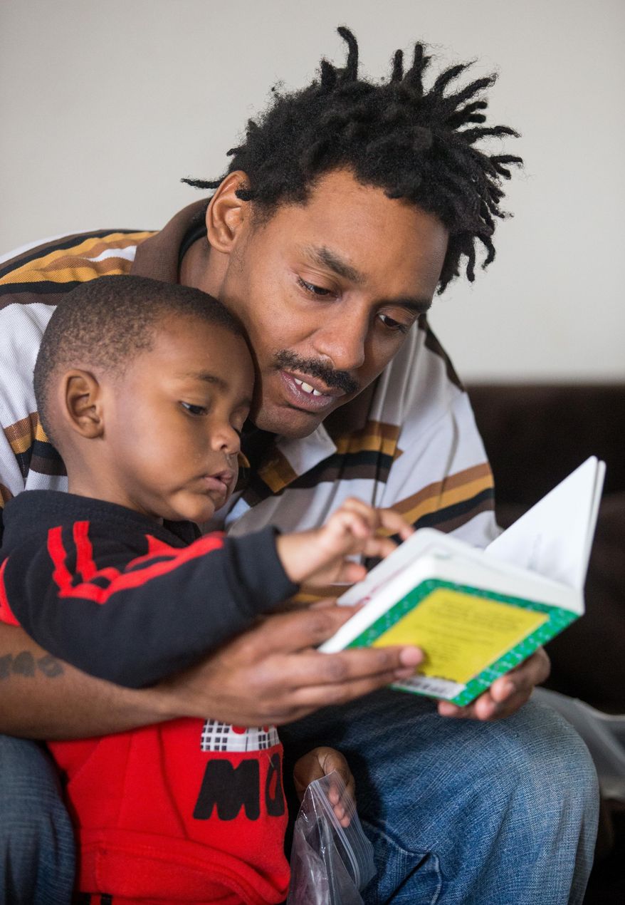 ADVANCE FOR WEEKEND EDITIONS, SATURDAY, FEB. 20- SUNDAY, FEB. 21, 2016- In this photo taken on Wednesday, Jan. 27, 2016, Ricky Lessley reads to his son, Ricky Lesley at their home in Omaha, Neb. The Learning Community is dispatching home visitors to instruct low-income parents on how to interact with their infants and toddlers. (Matt Dixon /Omaha World-Herald via AP) MAGS OUT; ALL NEBRASKA LOCAL BROADCAST TELEVISION OUT; MANDATORY CREDIT