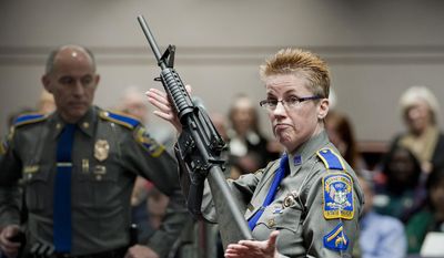 In this Jan. 28, 2013, file photo, firearms training unit Detective Barbara J. Mattson, of the Connecticut State Police, holds up a Bushmaster AR-15 rifle, the same make and model of gun used by Adam Lanza in the Sandy Hook School shooting, during a hearing of a legislative subcommittee, at the Legislative Office Building in Hartford, Conn. (AP Photo/Jessica Hill, File)