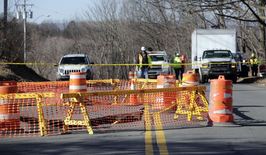 Barriers surround a sink hole on Campbell Avenue on Monday, Feb. 22, 2016, in Troy, N.Y. Officials believe the pavement gave way after a sewer line collapsed under the road early Sunday. The street remains closed as workers plan to use a camera to get a better look at the damage below ground in an effort to determine what repairs need to be made. (AP Photo/Mike Groll)