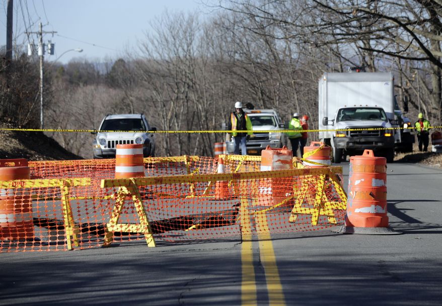 Barriers surround a sink hole on Campbell Avenue on Monday, Feb. 22, 2016, in Troy, N.Y. Officials believe the pavement gave way after a sewer line collapsed under the road early Sunday. The street remains closed as workers plan to use a camera to get a better look at the damage below ground in an effort to determine what repairs need to be made. (AP Photo/Mike Groll)
