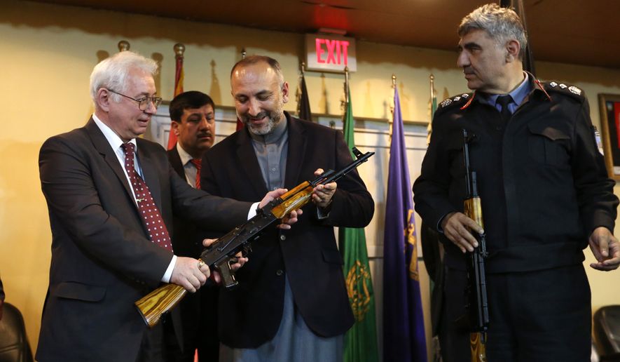 Russian Federation Ambassador, Alexander Mantytskiy, left, hands over an AK-47 to Afghan National Security Adviser Mohammad Hanif Atmar, center, as the symbol of his country&#39;s military donation to the Afghan government, at Kabul International Airport, Wednesday, Feb. 24, 2016. The Russian embassy in Kabul announced that the Russian government handed over 10,000 AK47s as a military donation to Afghan National Security Forces. (AP Photo/Rahmat Gul)