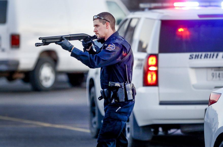 Police go through the parking lot of Excel Industries in Hesston, Kan., Thursday, Feb. 25, 2016, where a gunman killed an undetermined number of people and injured many more. (Fernando Salazar/The Wichita Eagle via AP)