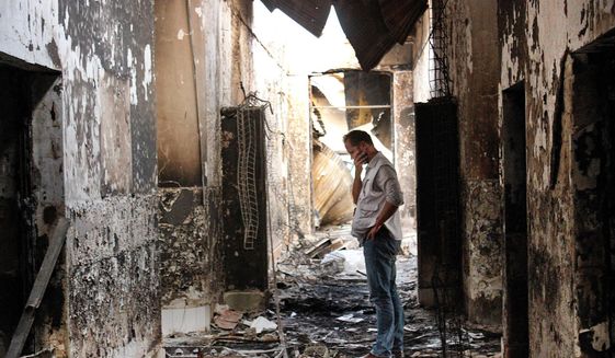 In this Friday, Oct. 16, 2015, file photo, an employee of Doctors Without Borders walks inside the charred remains of the organization&#39;s hospital after it was hit by a U.S. airstrike in Kunduz, Afghanistan. The U.S. military is paying hundreds of thousands of dollars to wounded survivors and relatives of the 42 Afghans killed when an American AC-130 gunship attacked the hospital; Doctors Without Borders says the “sorry money” doesn’t compensate for the loss of life. (AP Photo/Najim Rahim, File)
