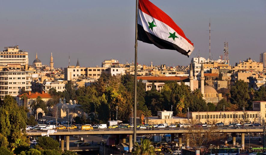A Syrian national flag waves as vehicles move slowly on a bridge during rush hour, in Damascus, Syria, Sunday, Feb. 28, 2016. (AP Photo/Hassan Ammar)