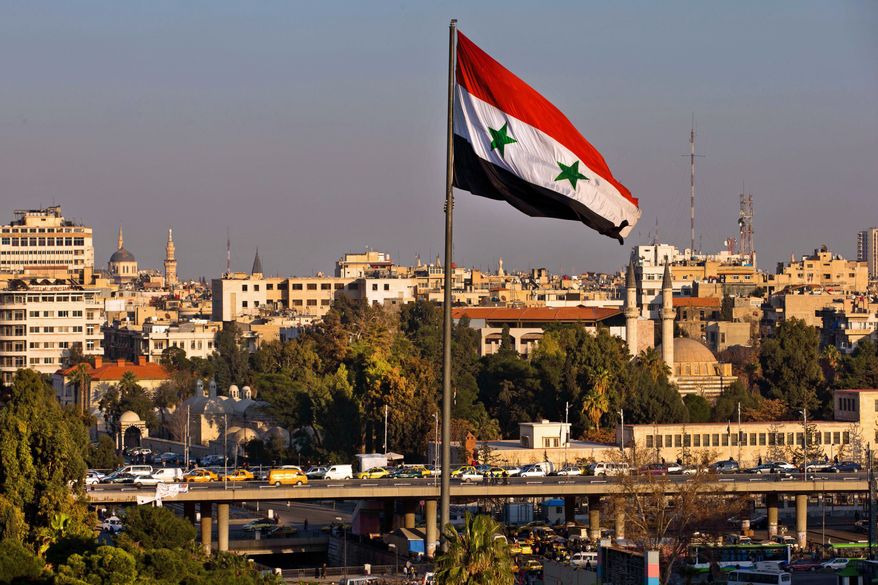 A Syrian national flag waves as vehicles move slowly on a bridge during rush hour, in Damascus, Syria, Sunday, Feb. 28, 2016. (AP Photo/Hassan Ammar)