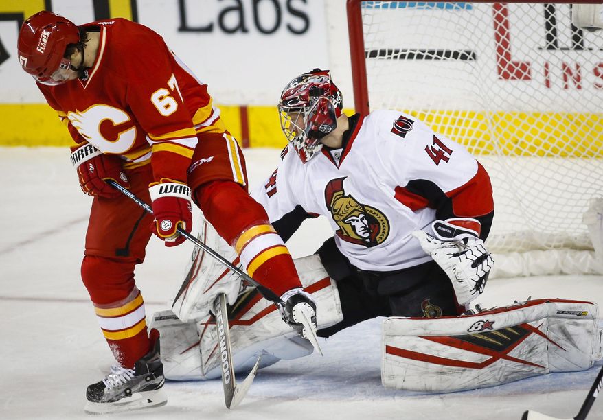 Ottawa Senators goalie Craig Anderson, right, kicks the puck away from Calgary Flames' Michael Frolik, from the Czech Republic, during the second period of an NHL hockey game Saturday, Feb. 27, 2016, in Calgary, Alberta. (Jeff McIntosh/The Canadian Press via AP)
