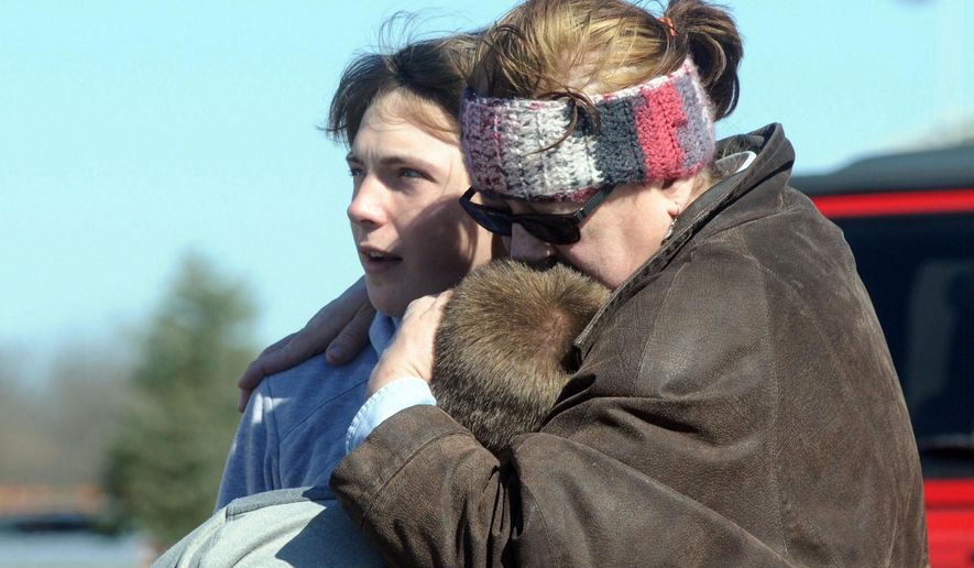 A child is comforted Monday, Feb. 29, 2016, near Middletown, Ohio after a school shooting at Madison Local Schools. An Ohio sheriff says a 14-year-old suspect in a school shooting that wounded four classmates, including two who were shot, is in a juvenile lock-up and facing several charges. Butler County Sheriff Richard Jones says the boy has been charged with two counts of attempted murder, two counts of felonious assault, inducing panic and making terrorist threats. (Marshall Gorby/Dayton Daily News via AP)
