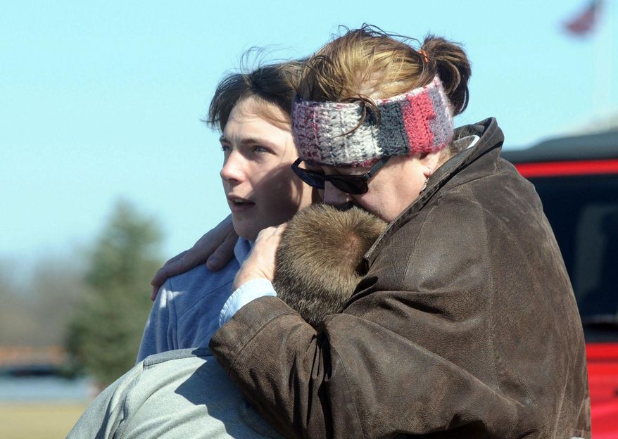 A child is comforted Monday, Feb. 29, 2016, near Middletown, Ohio after a school shooting at Madison Local Schools. An Ohio sheriff says a 14-year-old suspect in a school shooting that wounded four classmates, including two who were shot, is in a juvenile lock-up and facing several charges. Butler County Sheriff Richard Jones says the boy has been charged with two counts of attempted murder, two counts of felonious assault, inducing panic and making terrorist threats. (Marshall Gorby/Dayton Daily News via AP)